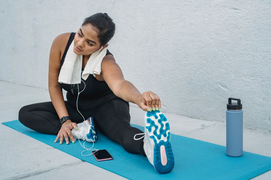Woman stretching on yoga mat outdoors, showcasing a healthy lifestyle.