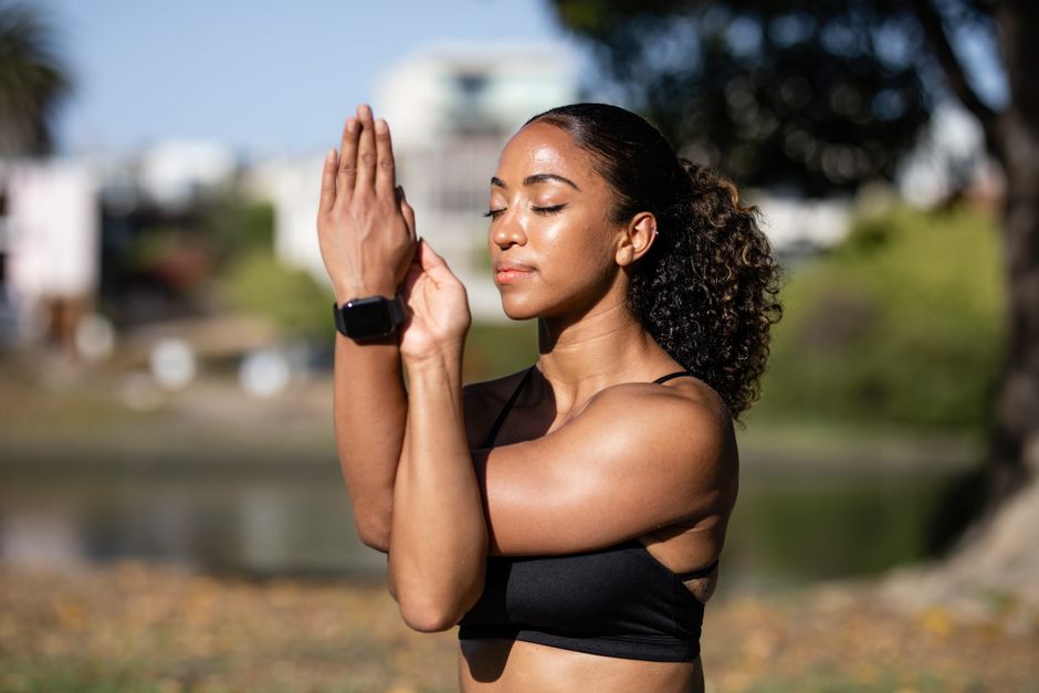 African American woman meditating outdoors, exuding relaxation and wellness.